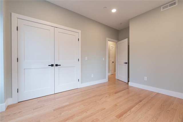 unfurnished bedroom featuring a closet, visible vents, light wood-style flooring, and baseboards