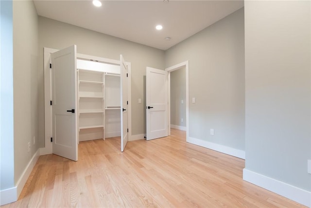 unfurnished bedroom featuring baseboards, a walk in closet, light wood-style floors, a closet, and recessed lighting