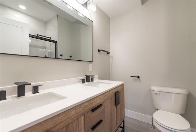 bathroom featuring toilet, a shower with door, baseboards, and a sink