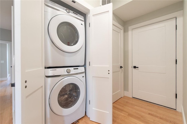 laundry area with light wood-style floors, stacked washer / dryer, and laundry area