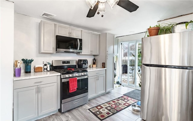 kitchen with stainless steel appliances, visible vents, light wood-style floors, light countertops, and gray cabinets