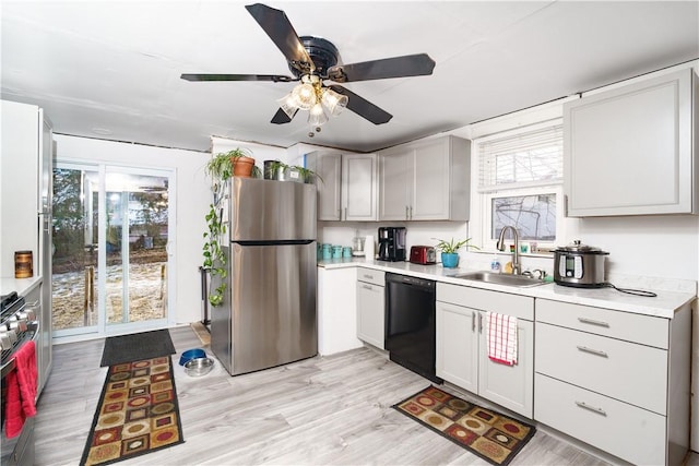 kitchen with stainless steel appliances, a sink, light countertops, and a healthy amount of sunlight