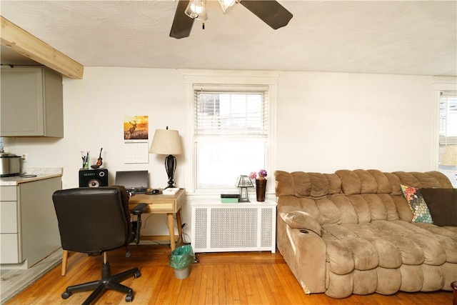 interior space featuring a ceiling fan, radiator, and light wood finished floors