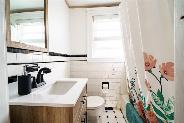 full bathroom featuring toilet, vanity, a wealth of natural light, and tile walls