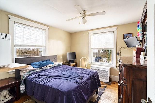 bedroom featuring baseboards, ceiling fan, wood finished floors, and radiator