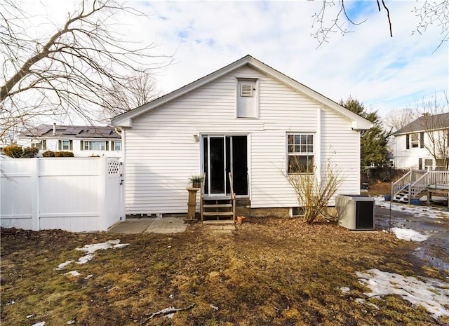 rear view of house featuring entry steps and fence