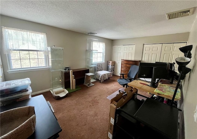 office area featuring carpet, visible vents, and a textured ceiling