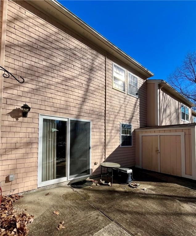 back of property with a patio area, a storage unit, and an outbuilding