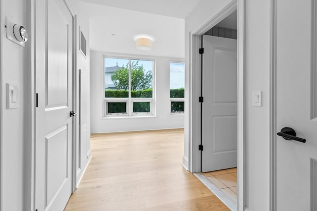 hallway featuring light wood-style floors and baseboards