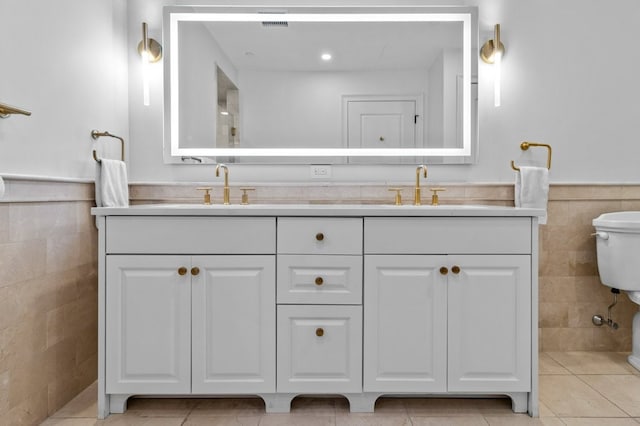 full bath featuring a wainscoted wall, a sink, tile walls, and toilet