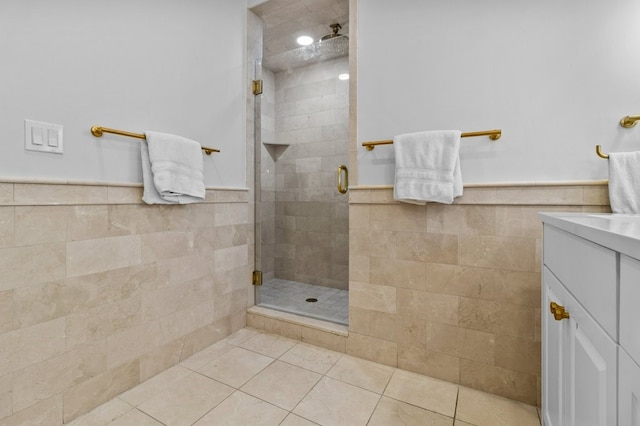 bathroom with wainscoting, a shower stall, tile walls, and tile patterned floors