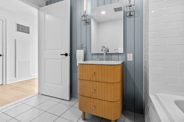 bathroom with vanity, tiled bath, tile patterned flooring, and visible vents