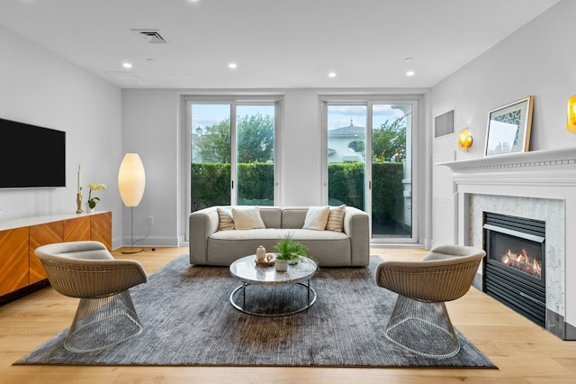 living room featuring a premium fireplace, wood finished floors, visible vents, and recessed lighting