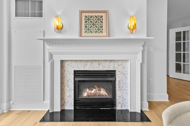 room details with baseboards, a fireplace, visible vents, and wood finished floors