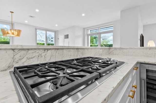 interior details featuring tasteful backsplash, visible vents, wine cooler, light stone countertops, and stovetop