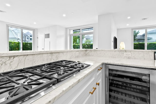 kitchen featuring light stone counters, wine cooler, stainless steel gas cooktop, recessed lighting, and white cabinetry