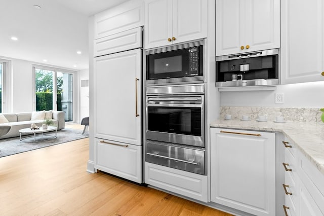 kitchen with built in appliances, white cabinetry, light wood-style floors, open floor plan, and a warming drawer