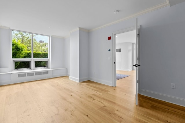 unfurnished room featuring light wood-type flooring, radiator, baseboards, and crown molding