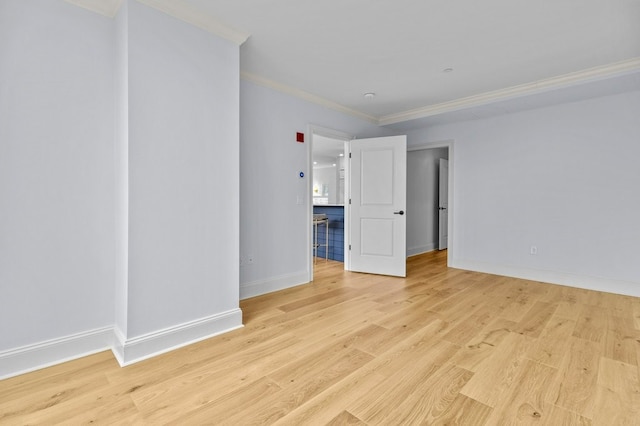 unfurnished room featuring baseboards, light wood finished floors, and crown molding