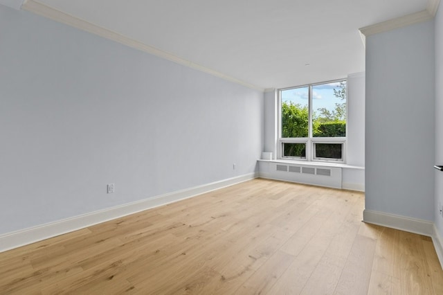 empty room with radiator heating unit, baseboards, crown molding, and light wood finished floors