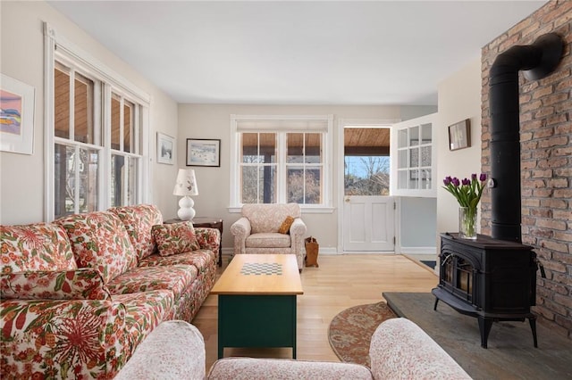 living room featuring wood finished floors, a wood stove, and baseboards