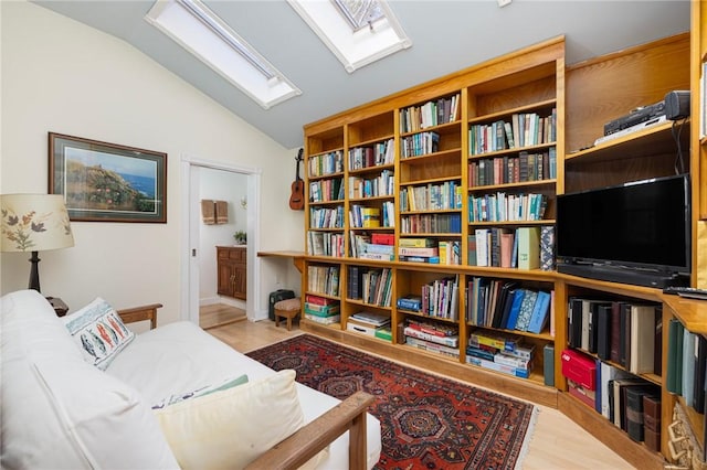 living area featuring lofted ceiling with skylight and wood finished floors