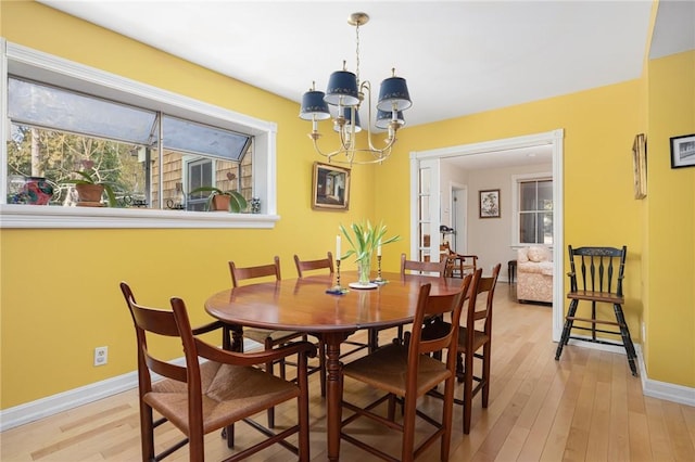 dining space featuring light wood-style floors, a chandelier, and baseboards