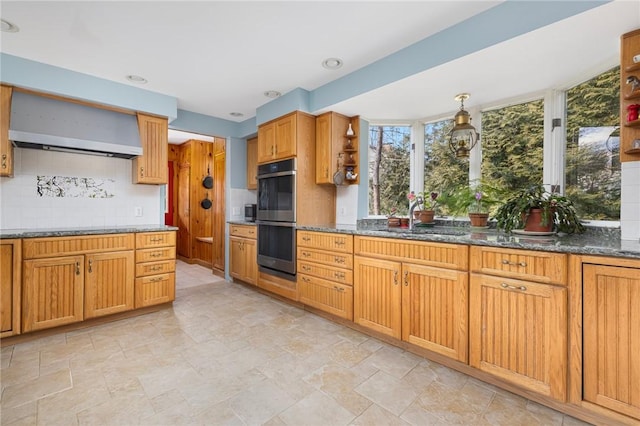 kitchen with wall chimney range hood, stainless steel double oven, open shelves, and a sink