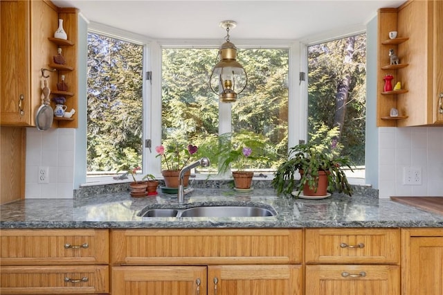 kitchen with dark stone counters, a sink, and open shelves