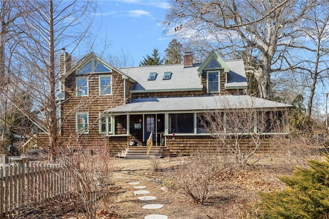 shingle-style home with a sunroom, roof with shingles, fence, and a chimney