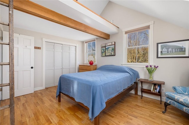 bedroom with vaulted ceiling with beams, a closet, baseboards, and light wood-style floors