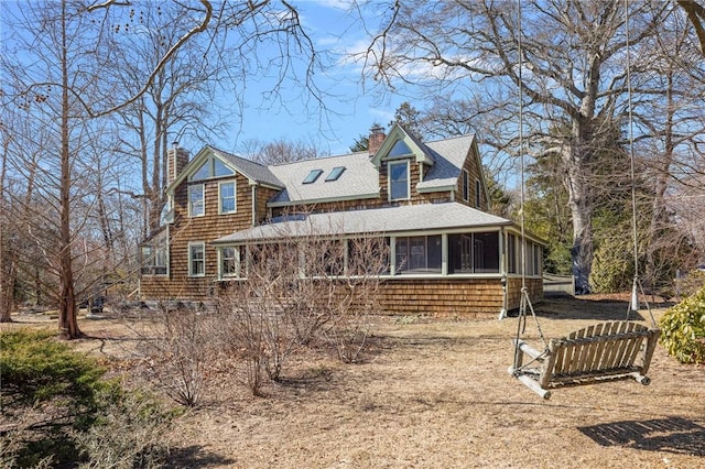 exterior space featuring a sunroom, roof with shingles, and a chimney