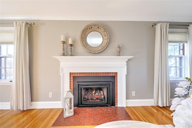 room details with crown molding, a fireplace, wood finished floors, and baseboards