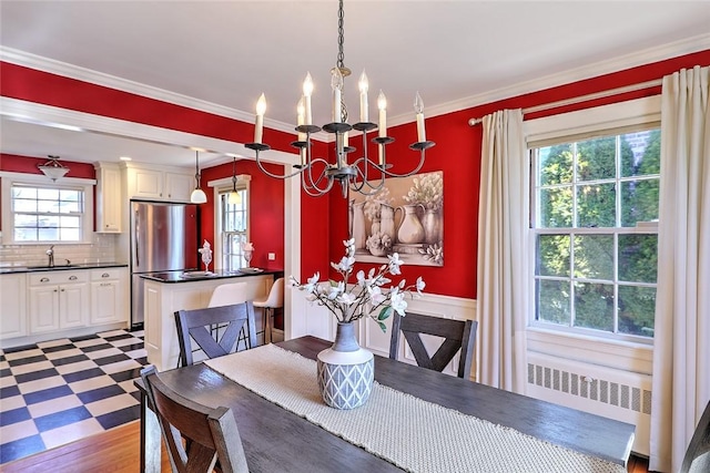 dining space featuring light floors, radiator heating unit, ornamental molding, and an inviting chandelier