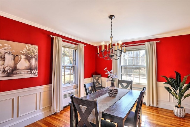 dining space with radiator, a wainscoted wall, light wood-style flooring, and a wealth of natural light