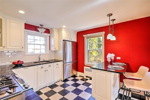 kitchen featuring a sink, freestanding refrigerator, tile patterned floors, radiator heating unit, and dark countertops