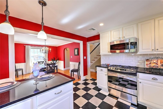 kitchen with dark floors, stainless steel appliances, dark countertops, visible vents, and white cabinets