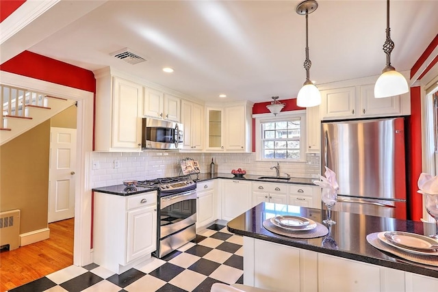 kitchen with visible vents, dark countertops, stainless steel appliances, light floors, and a sink