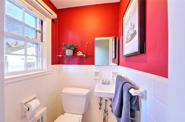 bathroom featuring a wainscoted wall, tile walls, toilet, and a healthy amount of sunlight