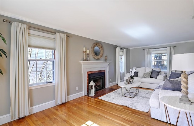 living area featuring a brick fireplace, light wood-style flooring, and baseboards