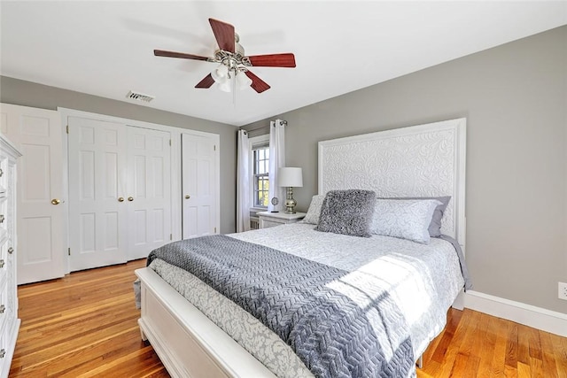 bedroom featuring light wood-style floors, visible vents, ceiling fan, and baseboards