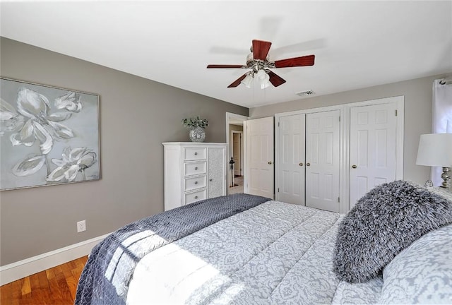 bedroom featuring visible vents, ceiling fan, baseboards, and wood finished floors