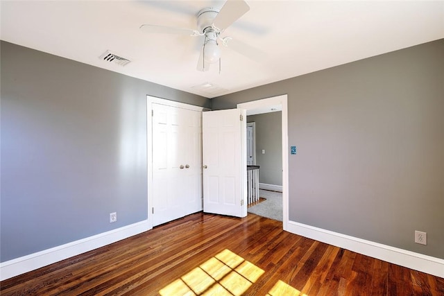 unfurnished bedroom with baseboards, a closet, visible vents, and wood finished floors