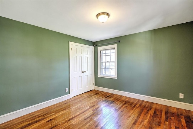 empty room with wood-type flooring and baseboards