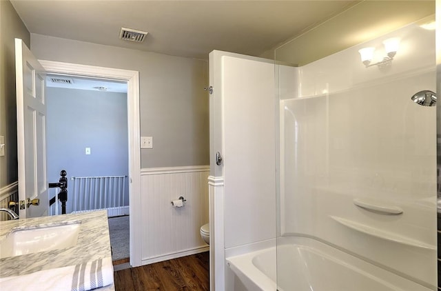 bathroom featuring toilet, wainscoting, wood finished floors, and visible vents