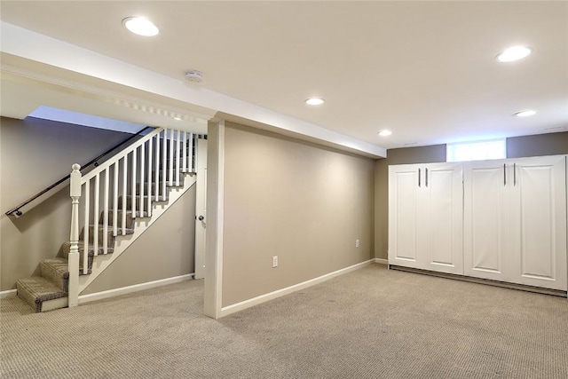 below grade area with recessed lighting, light colored carpet, stairway, and baseboards