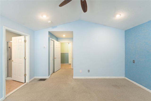 empty room with lofted ceiling, baseboards, a ceiling fan, and light colored carpet