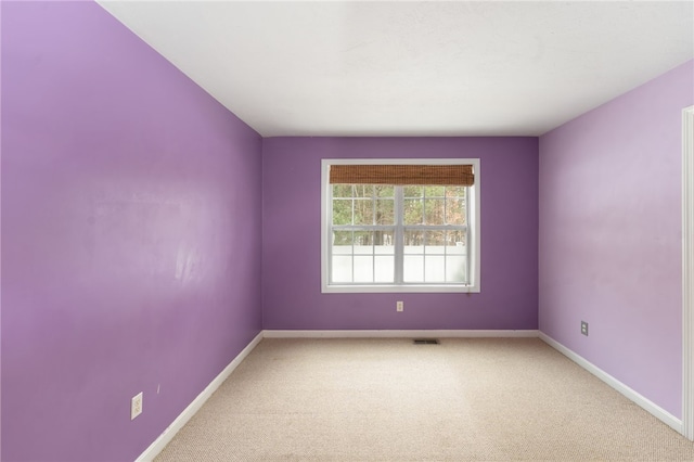 spare room featuring light carpet, visible vents, and baseboards