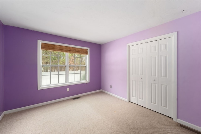 unfurnished bedroom featuring a closet, baseboards, visible vents, and carpet flooring