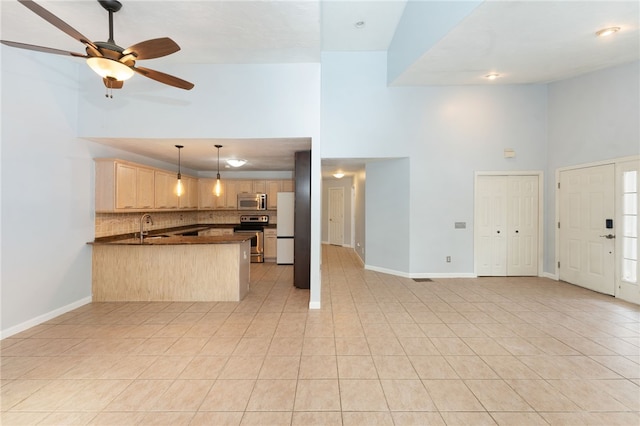 kitchen with high vaulted ceiling, stainless steel appliances, a peninsula, light brown cabinetry, and dark countertops